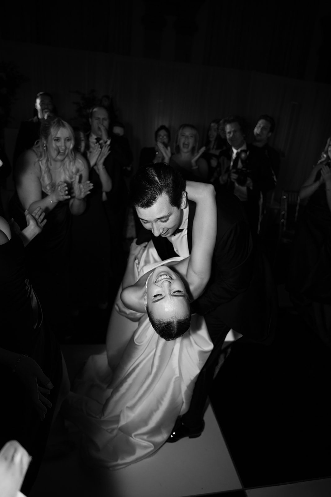 Black and white photo of wedding couple dancing at their reception with the bride being dipped by her husband