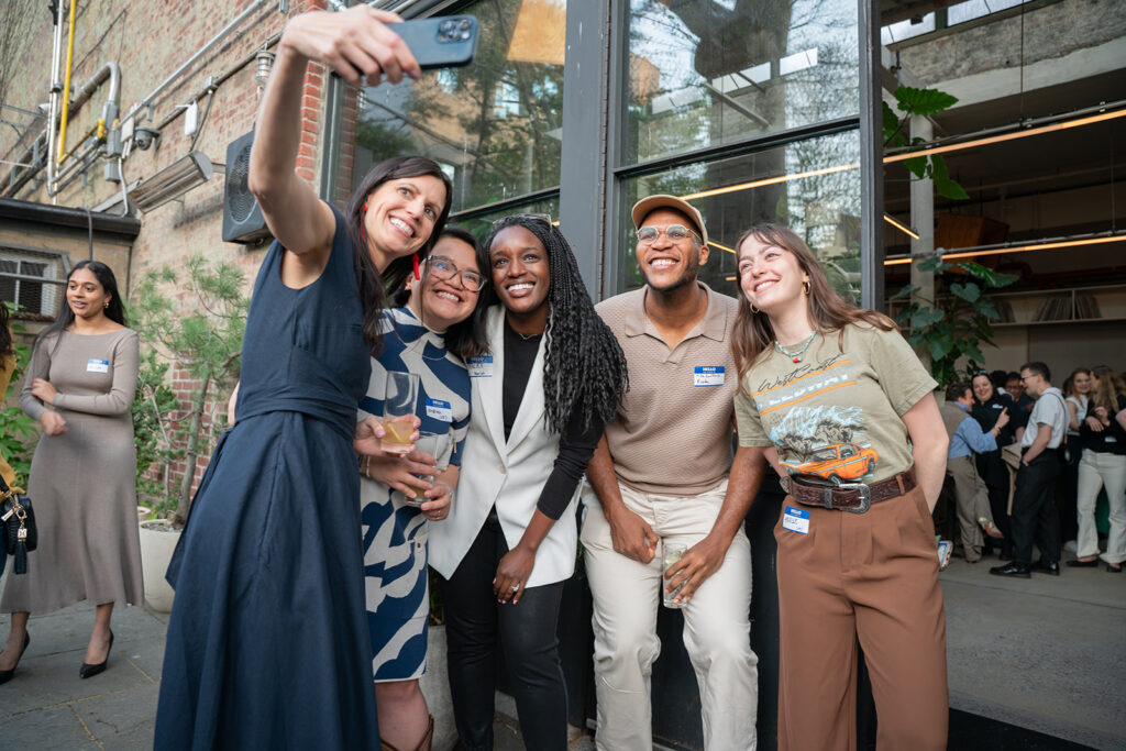 a group of mixed races/cultures of people taking a selfie smiling at the Youth Power Fund opening dinner at Public Records in Brooklyn NY for Prince Harry and Meagan Markle's Foundation