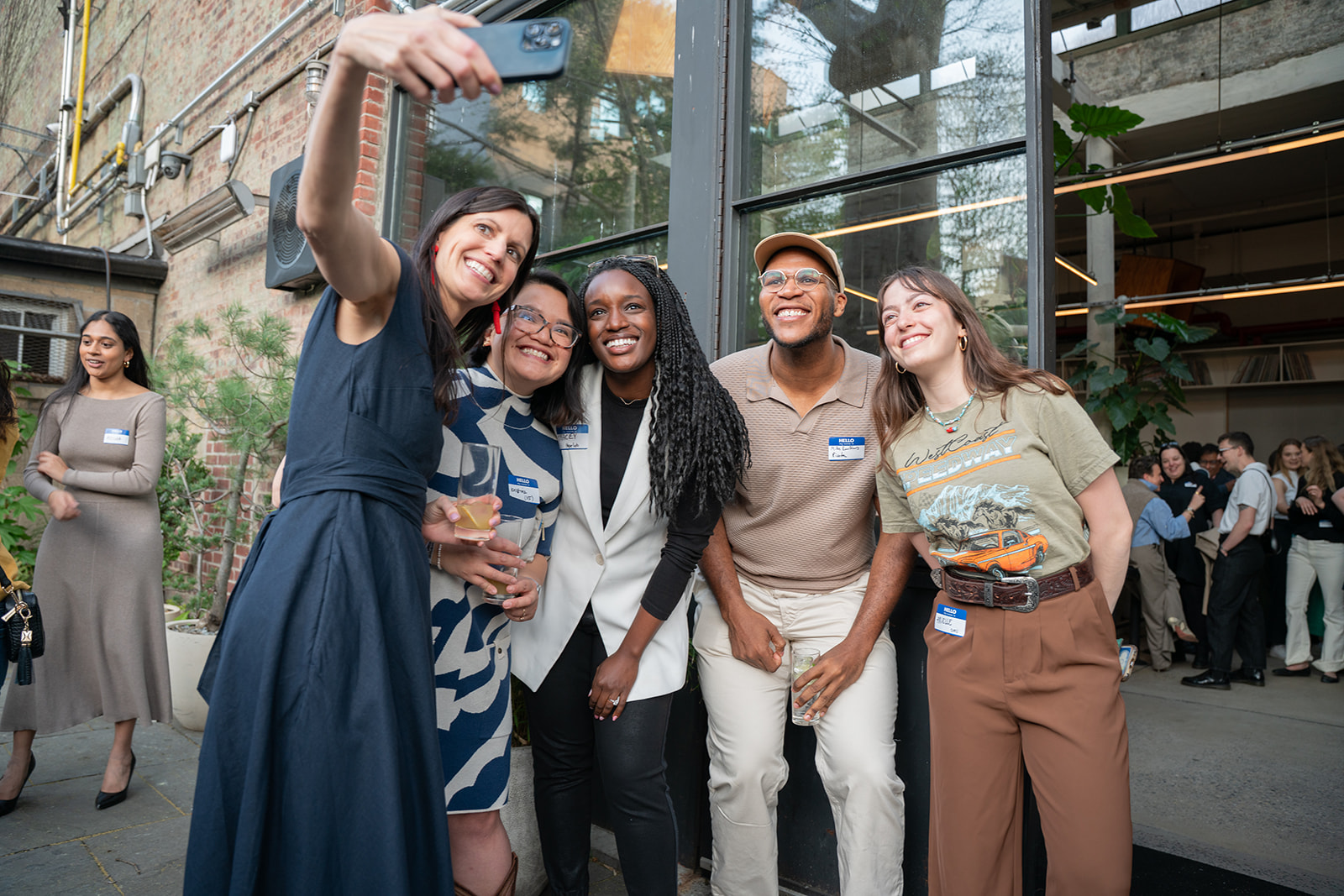 a group of mixed races/cultures of people taking a selfie smiling at the Youth Power Fund opening dinner at Public Records in Brooklyn NY for Prince Harry and Meagan Markle's Foundation